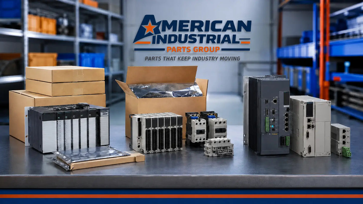 A collection of industrial electrical components, control modules, and cardboard boxes displayed on a table in a warehouse setting, with the 'American Industrial Parts Group' logo visible in the background.